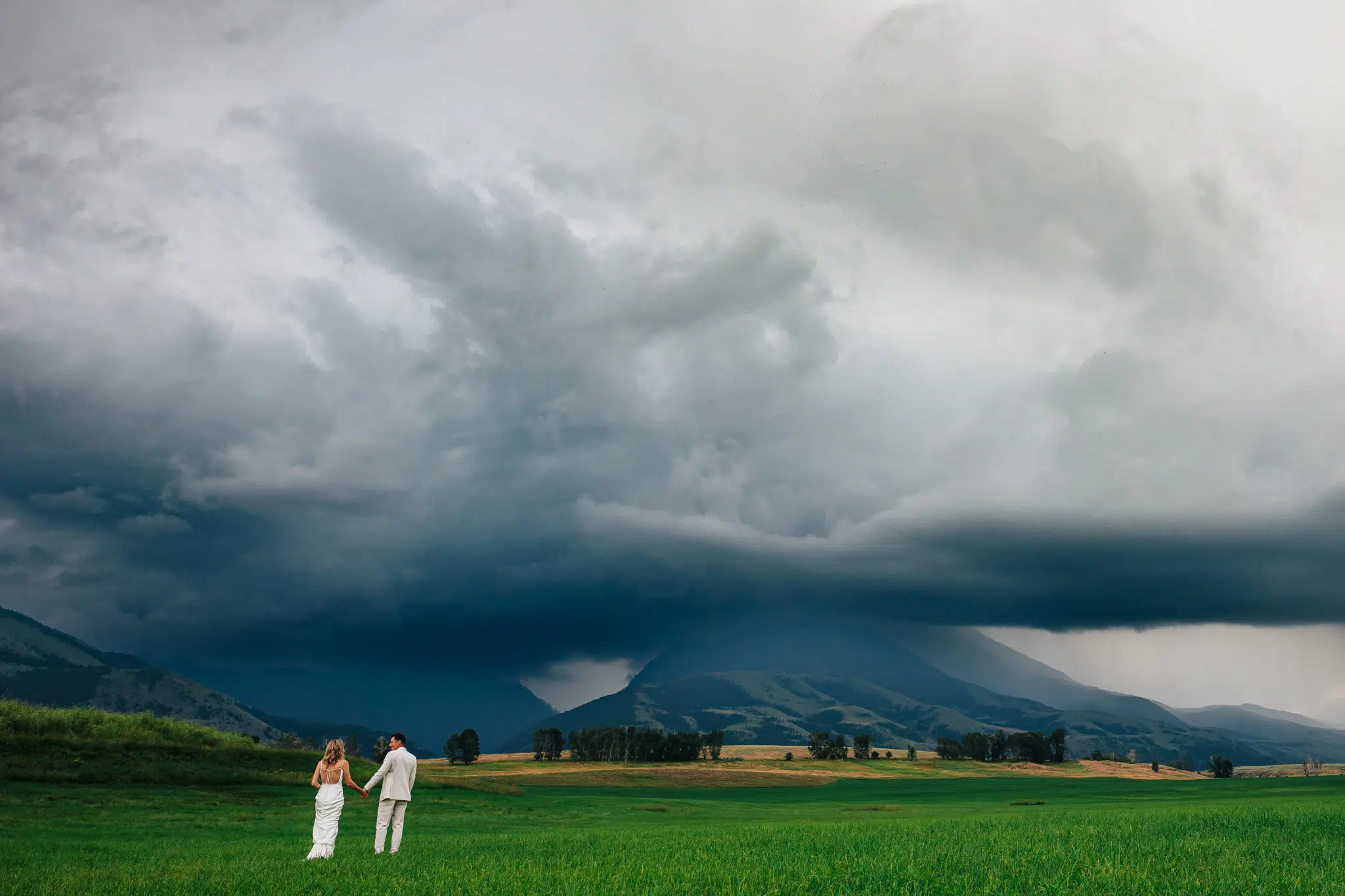 At Sage Lodge, A Couple Poses With A Dramatic Stormy Sky As Their Backdrop. Image Courtesy Of Charles Moll, A Premier Montana Elopement Photographer
